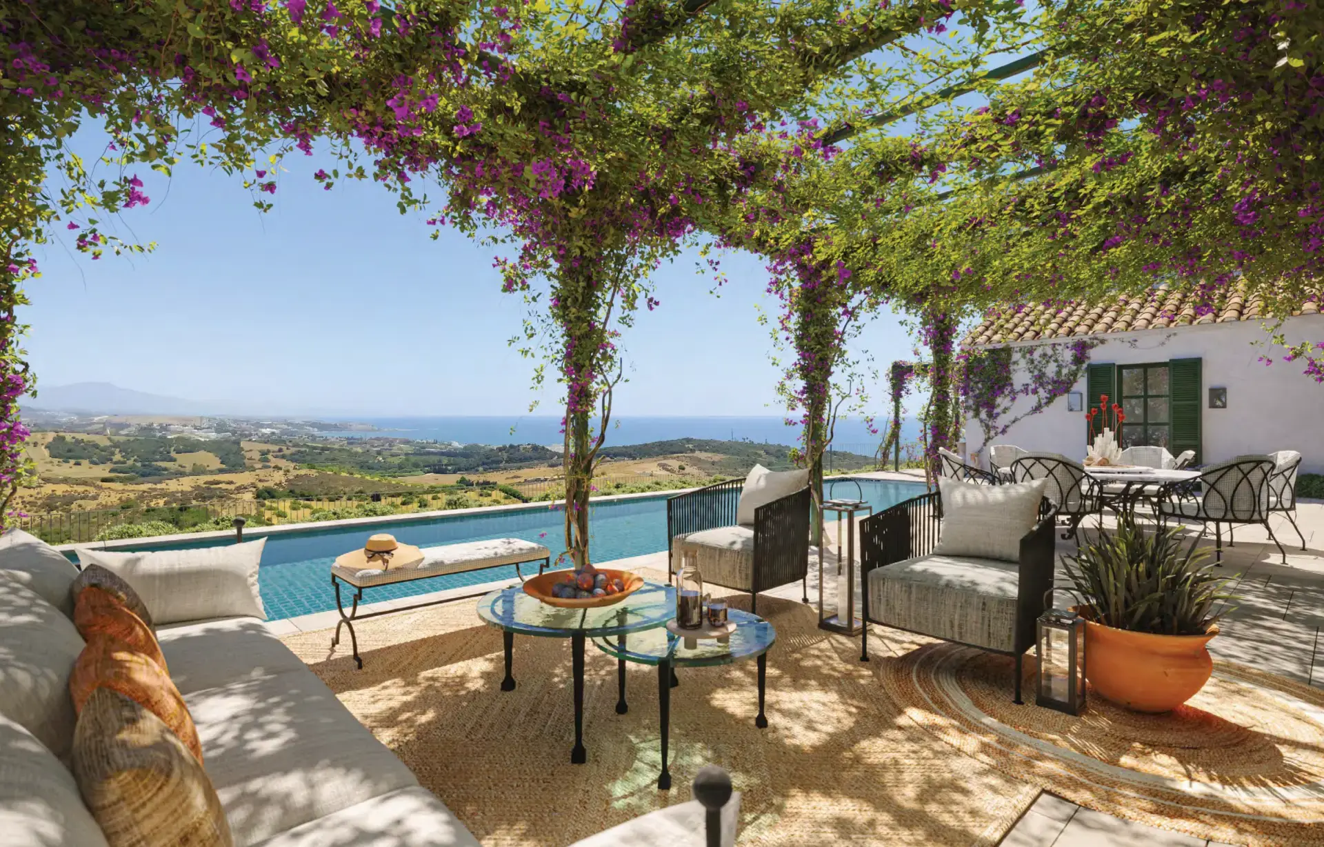 Terrace under a bougainvillea pergola, with a pool and sea views